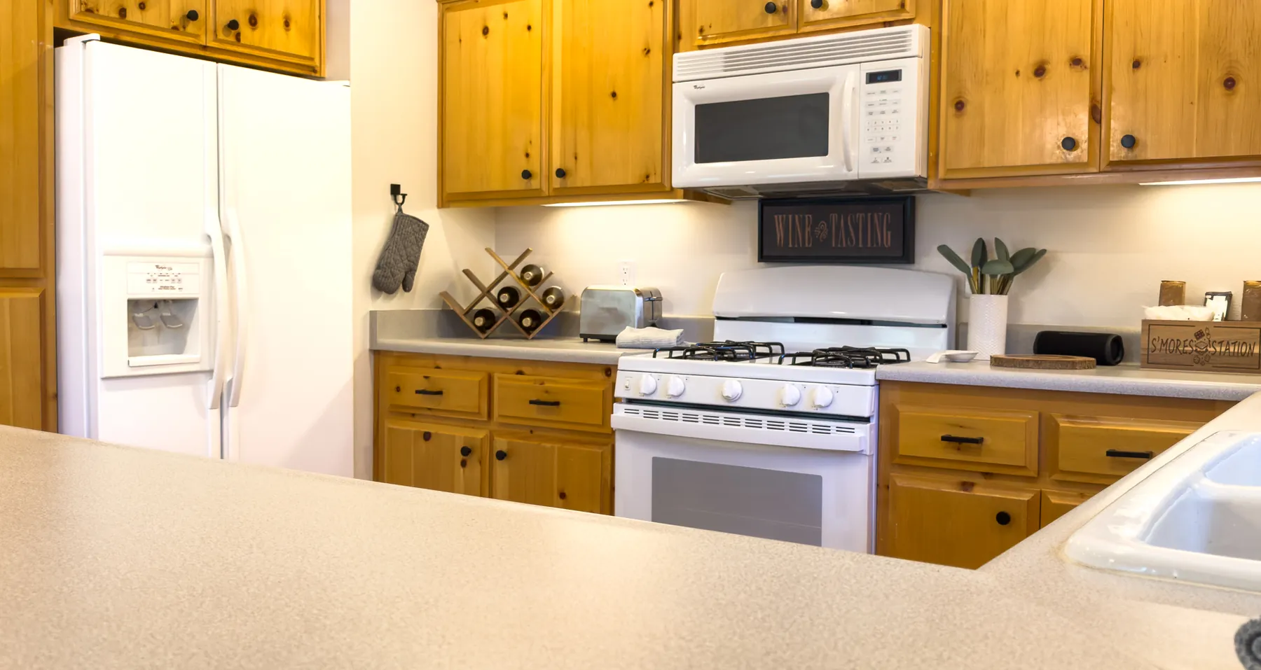 Kitchen at Pine Grove Cabin with knotty pine cabinets, refrigerator, gas range, and microwave
